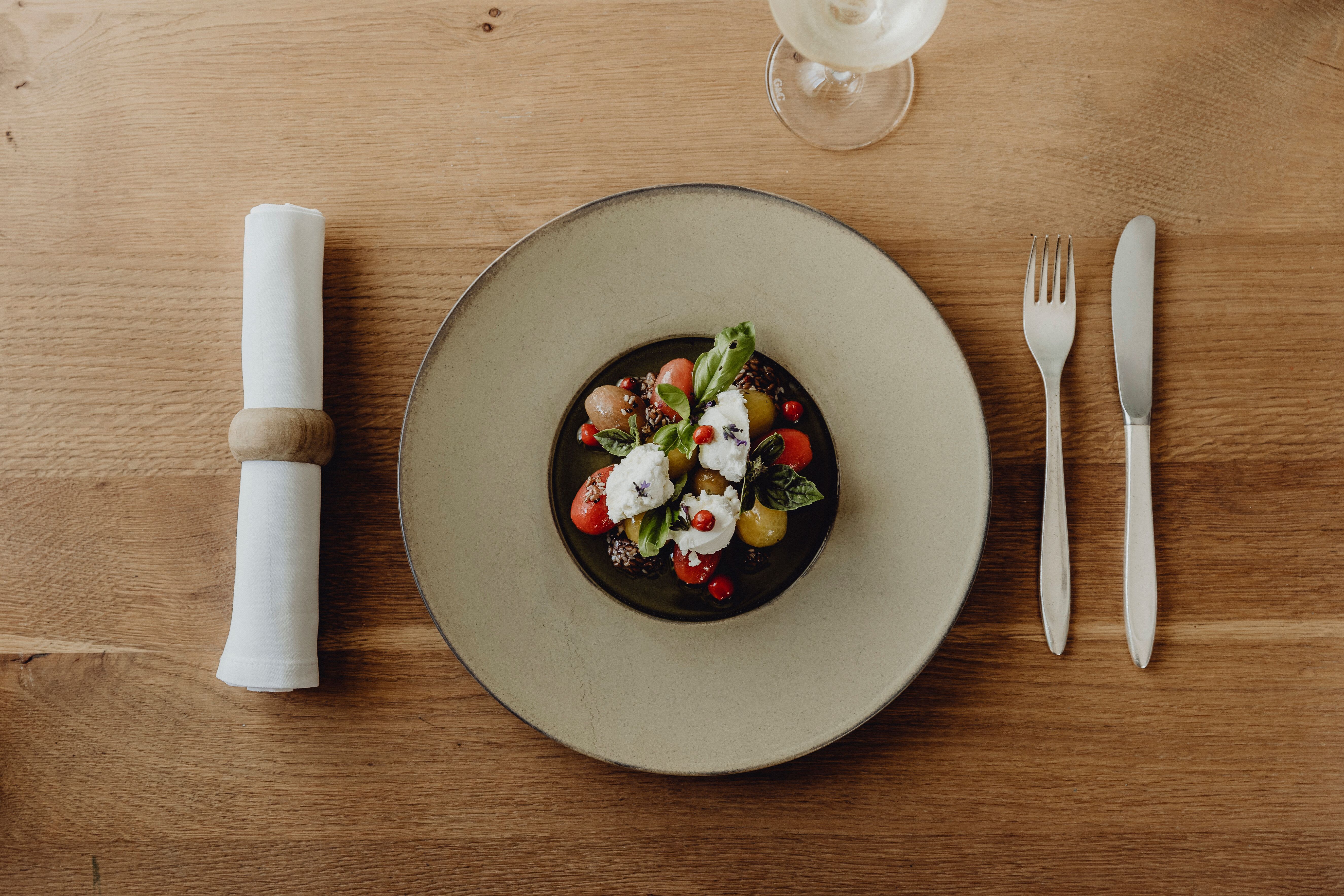 Ein kunstvoll angerichteter Teller vereint frische Tomaten und cremigen Mozzarella, garniert mit aromatischen Kräutern. Diese kulinarische Köstlichkeit spiegelt die herzliche Gastfreundschaft und die regionale Küche wider, die im Landgasthof zur Linde zelebriert wird.