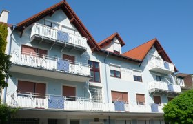 Mehrstöckiges Gebäude mit blauer Fassade und roten Dächern.