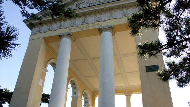 Der Husarentempel mit Säulen und Reliefs, umgeben von Bäumen.