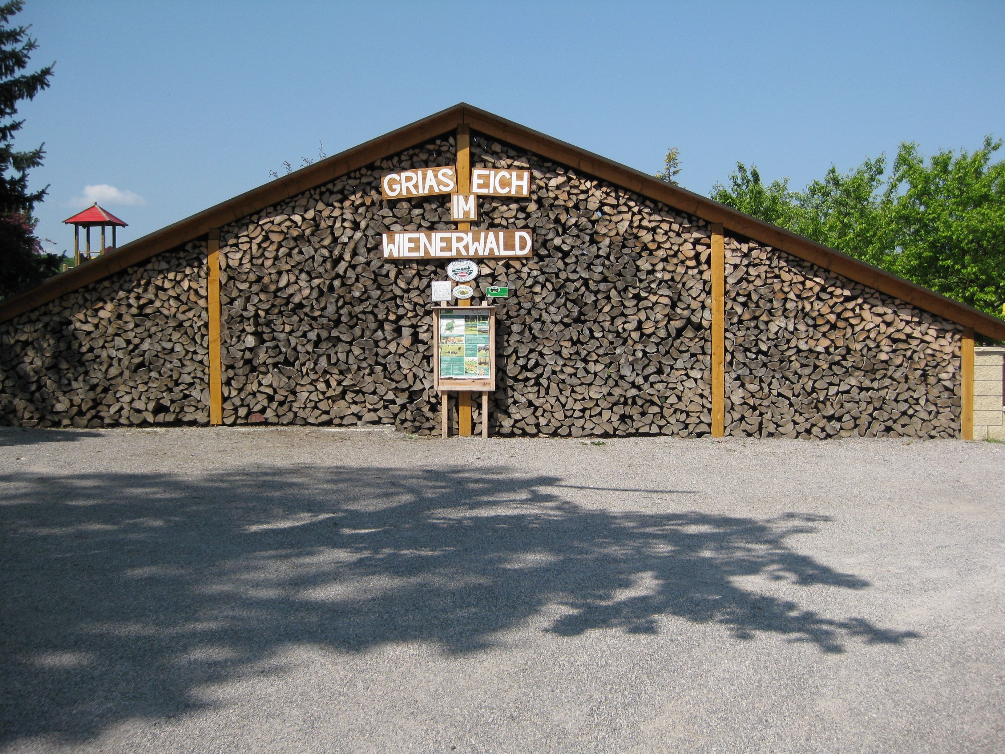 Holzstapel mit Schild 'Griaß Eich im Wienerwald'.