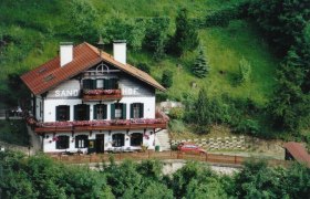 Traditionelles Haus namens Sand-Hof in gr&uuml;ner Landschaft.