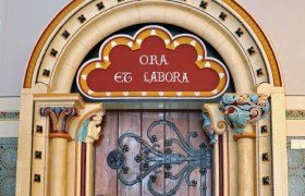 Decorated wooden door with Latin inscription 'Ora et Labora'.