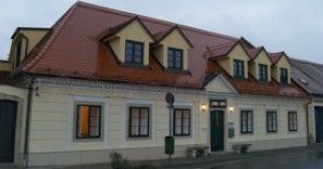 Zweistöckiges Gebäude mit gelber Fassade und rotem Dach.