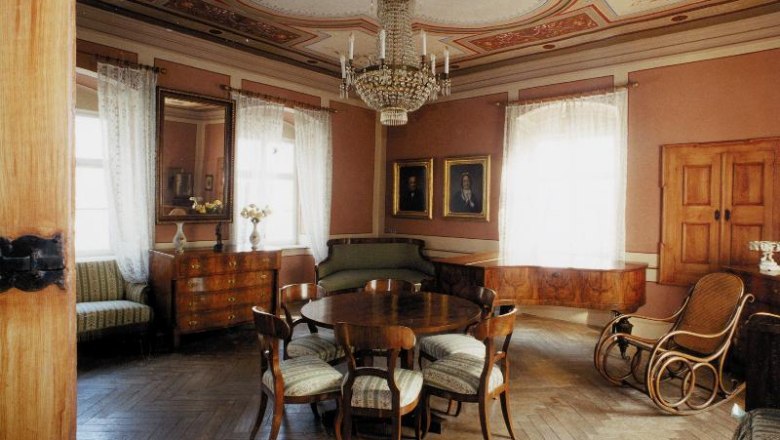 Elegantes Wohnzimmer im Hugo Wolf Haus mit antiken Möbeln und Kronleuchter.