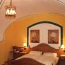 Cozy bedroom with wooden bed, yellow walls and vaulted ceiling.