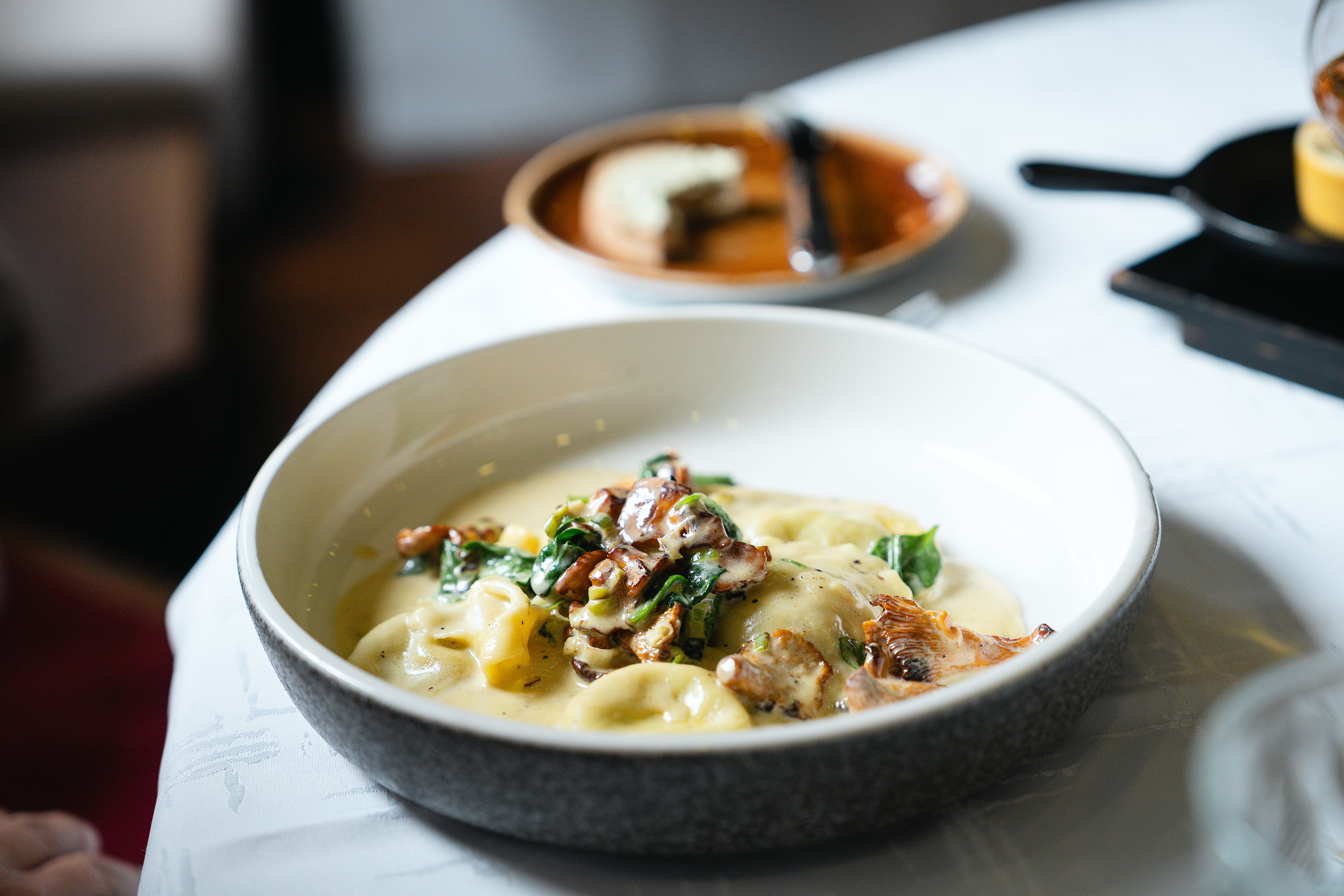 Fein angerichtetes Pastagericht mit Kräutern und Texturen wie gerösteten Zutaten und cremiger Sauce.