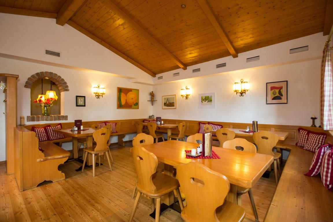 Gemütliche Stube mit Holzmöbeln, karierten Kissen und Wanddekorationen.