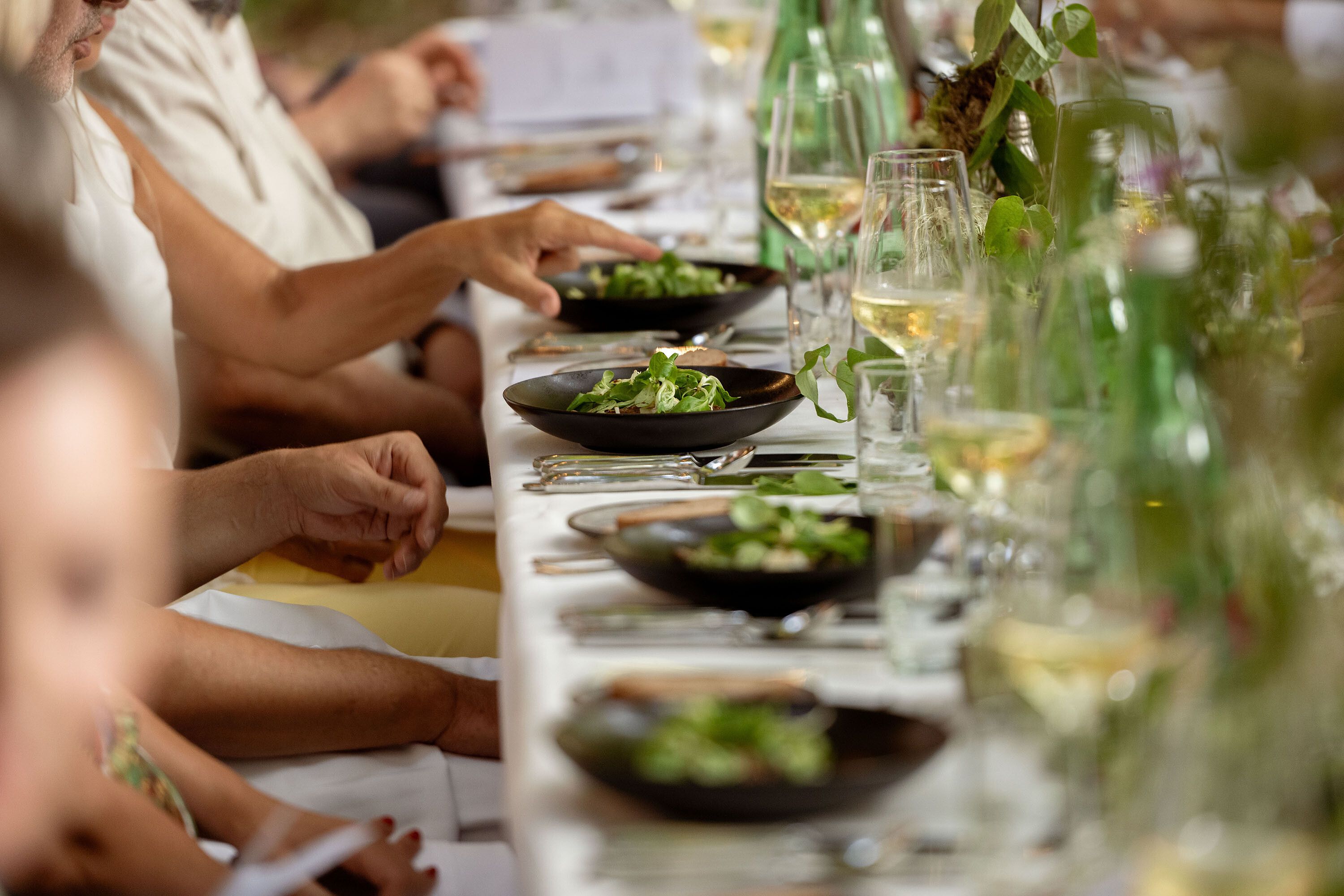 Ein festlich gedeckter Tisch lädt zu einem genussvollen Abendessen ein, umgeben von der malerischen Natur des Wienerwaldes. Die frischen Salate in eleganten Schalen versprechen kulinarische Höhepunkte, während die Gläser mit sprudelndem Wein auf gesellige Gespräche anstoßen.