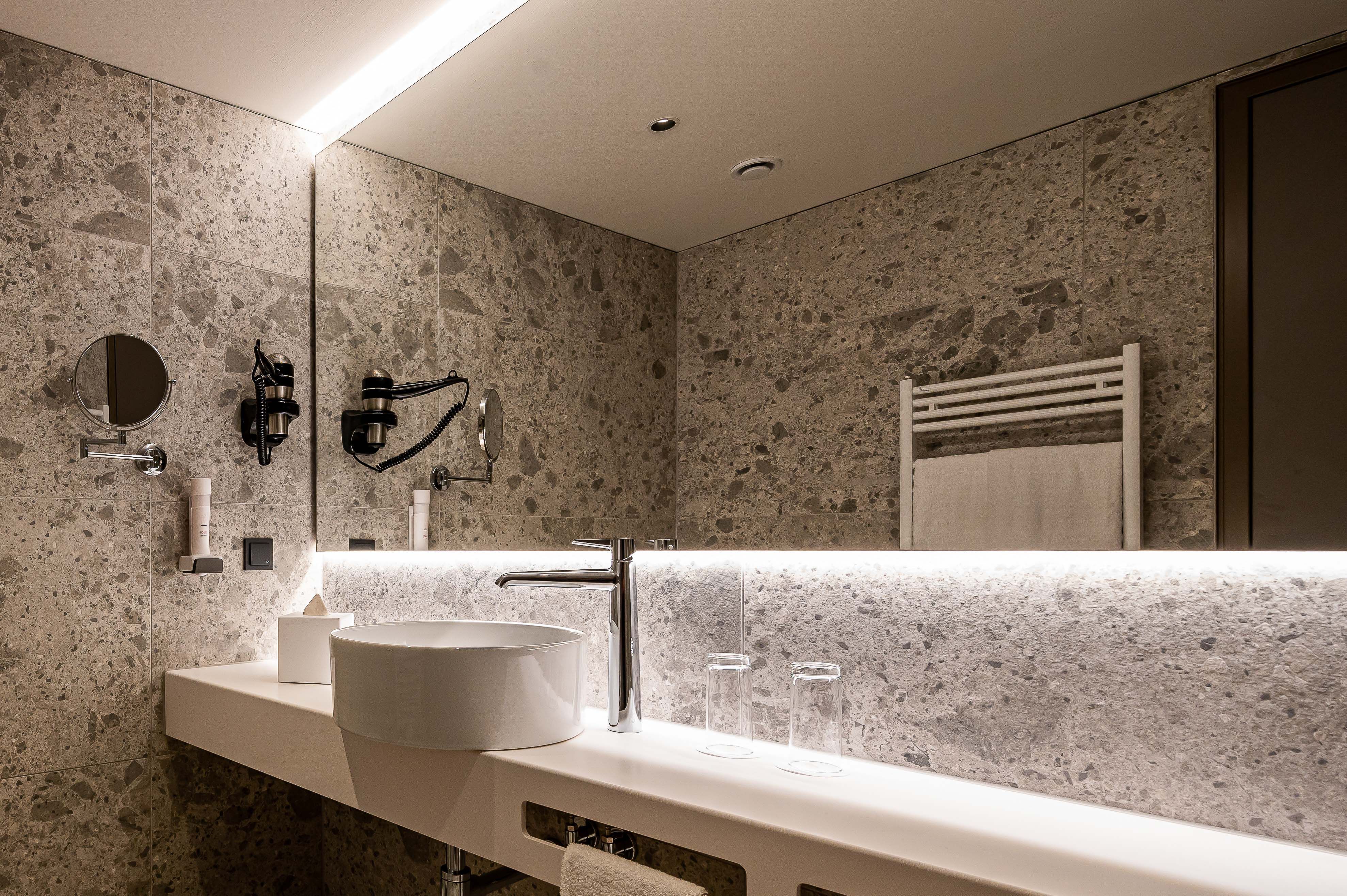 Modernes Badezimmer mit Waschbecken, Spiegel und Handtuchhalter.