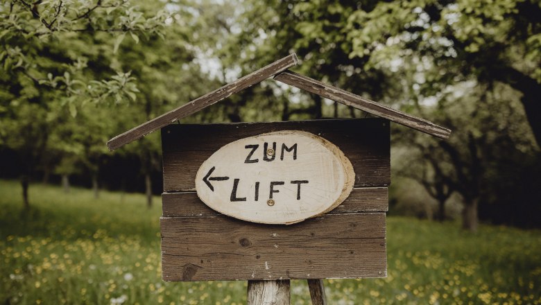 Holzschild im Grünen mit Aufschrift 'Zum Lift' und Pfeil nach links.
