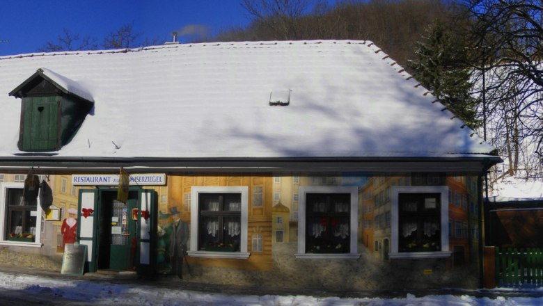 Ein verschneites Gebäude mit bemalter Fassade und der Aufschrift 'Restaurant Kaiserziegel'.