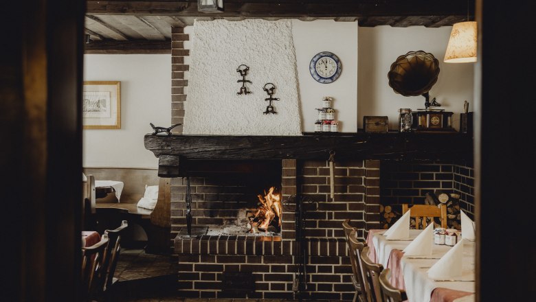 Gemütliches Restaurant mit Kamin, rustikaler Einrichtung und gedecktem Tisch.