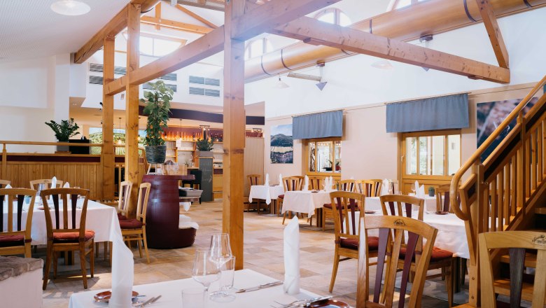 Interior view of a restaurant with wooden elements and laid tables.