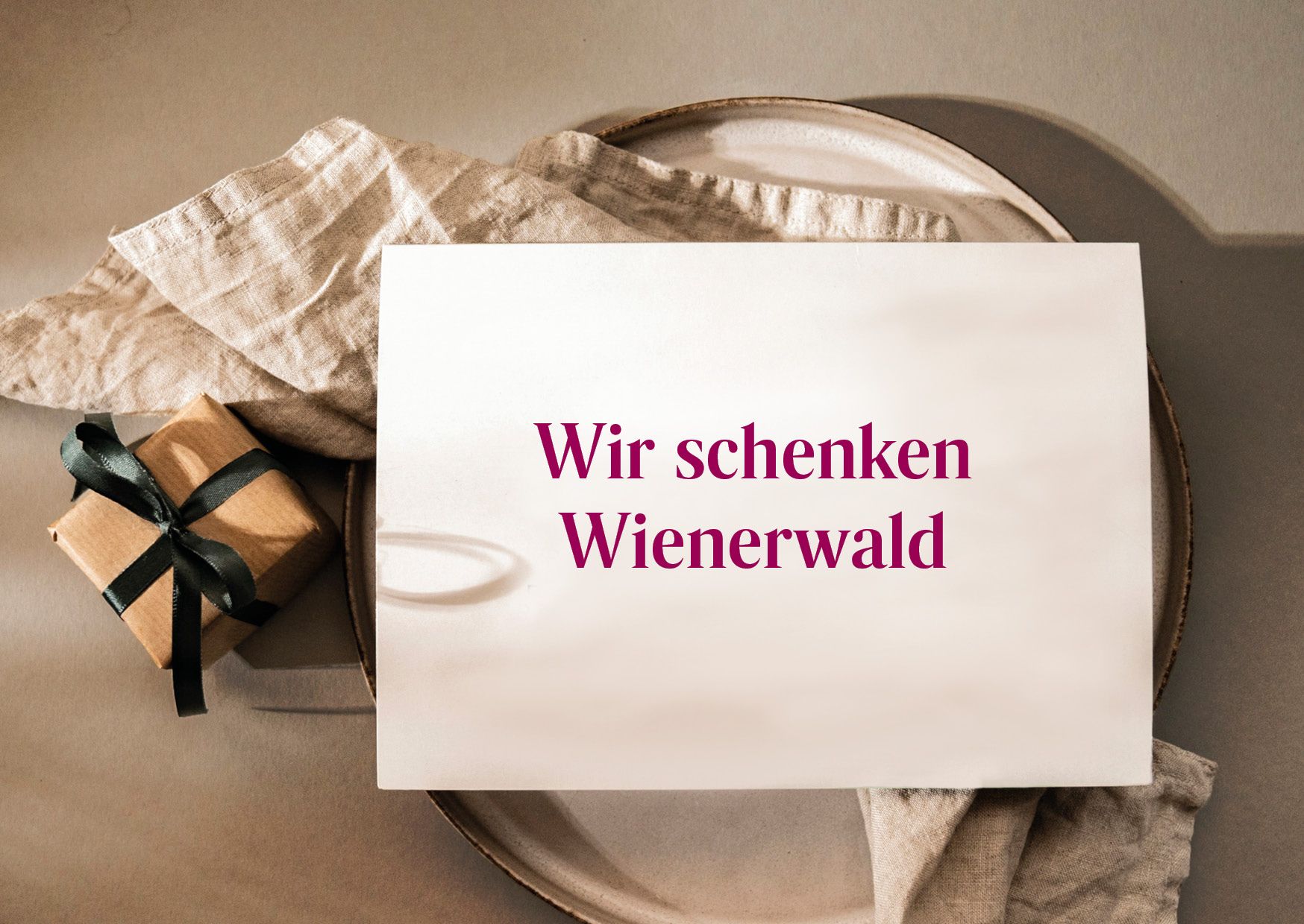 Auf einem Teller angerichtet, liegt ein Tuch und ein kleines Päkchen mit einer Aufschrift Wir schenken Wienerwald.