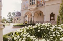 Umgeben von üppigen, blühenden Hortensien entfaltet sich die majestätische Fassade des Stadttheaters. Die kunstvollen Verzierungen und die harmonische Architektur laden dazu ein, in die kulturelle Vielfalt der Region einzutauchen. Ein Ort, an dem Kunst und Natur in perfekter Symbiose verschmelzen.