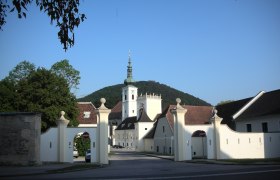 Entrance gate of Heiligenkreuz Abbey with church tower in the background.