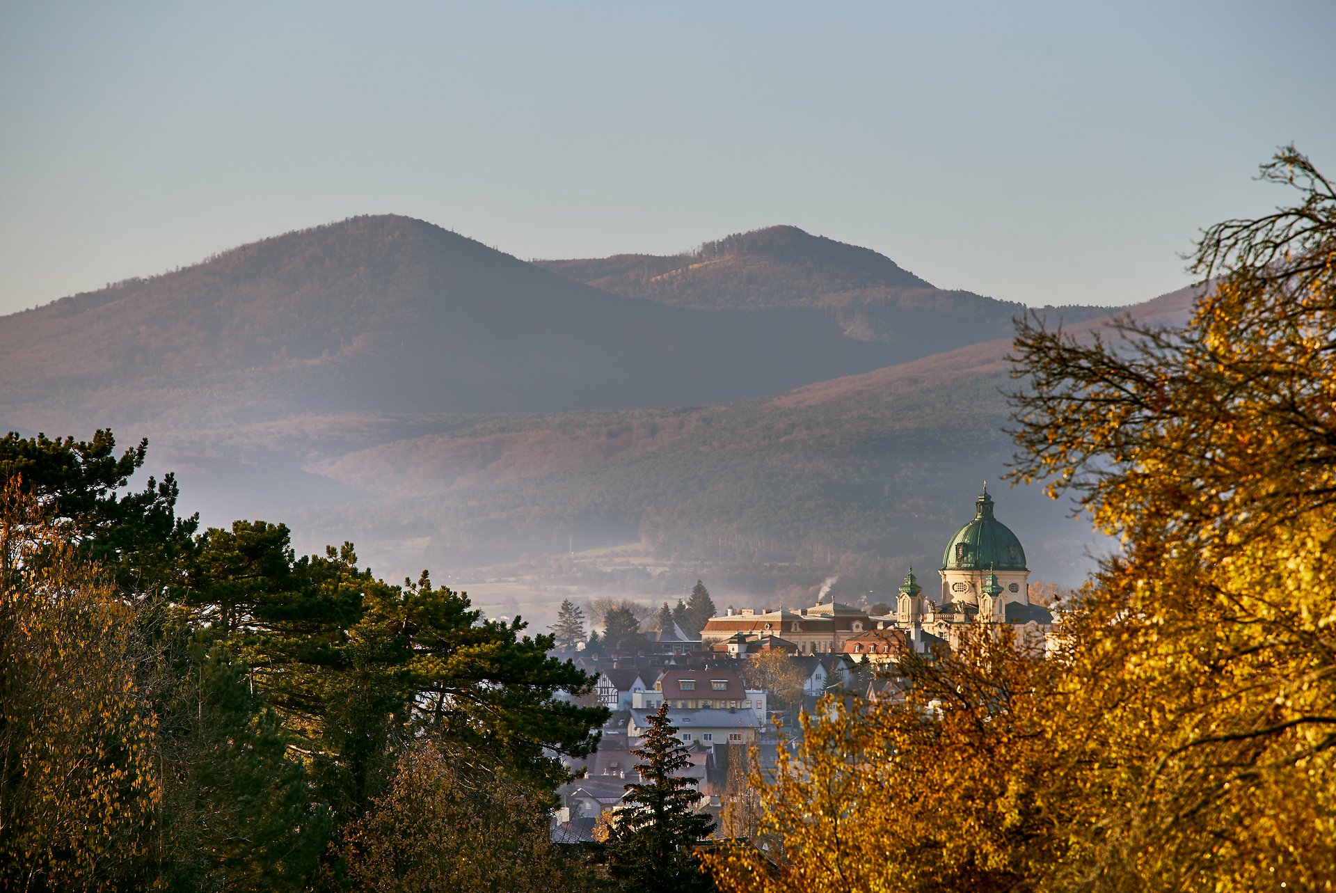 Die sanften Hügel des Wienerwaldes umarmen die malerische Stadt Berndorf, während die goldenen Blätter des Herbstes in der warmen Sonne leuchten. Ein sanfter Nebel schwebt über dem Triestingtal und verleiht der Landschaft eine mystische Atmosphäre, die zum Verweilen und Entdecken einlädt.