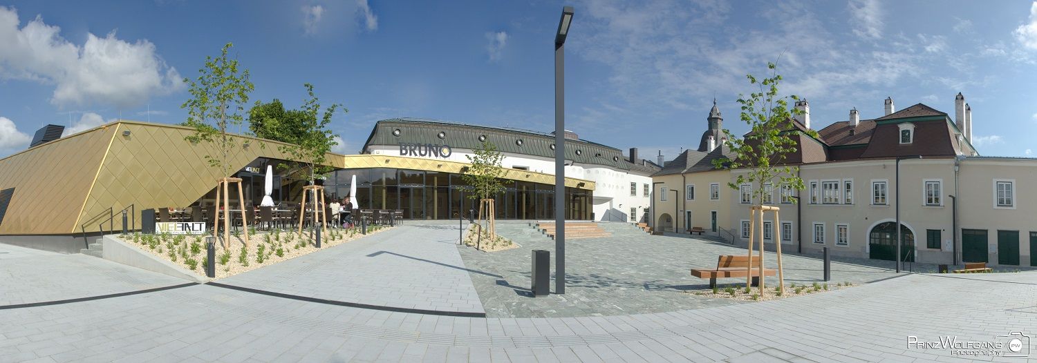 Moderne Architektur mit goldener Fassade und traditionellem Gebäude im Hintergrund, blauer Himmel.
