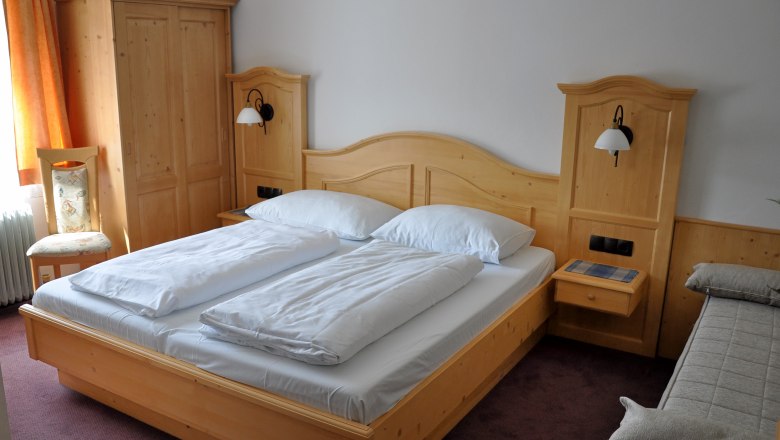 Comfort room with double bed and solid wood furniture.