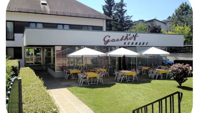 Außenansicht des Gasthofs Gerhart mit Terrasse und Sonnenschirmen.