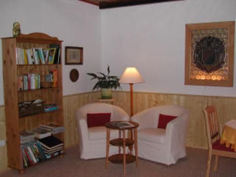 Gemütliche Sitzecke mit zwei Sesseln, einem kleinen Tisch, Bücherregal und Stehlampe.