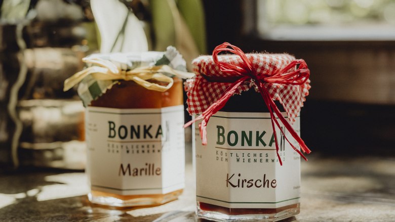 Zwei Gläser Marmelade mit Etiketten 'Bonka', eins mit Marille, das andere mit Kirsche, auf einem Tisch.
