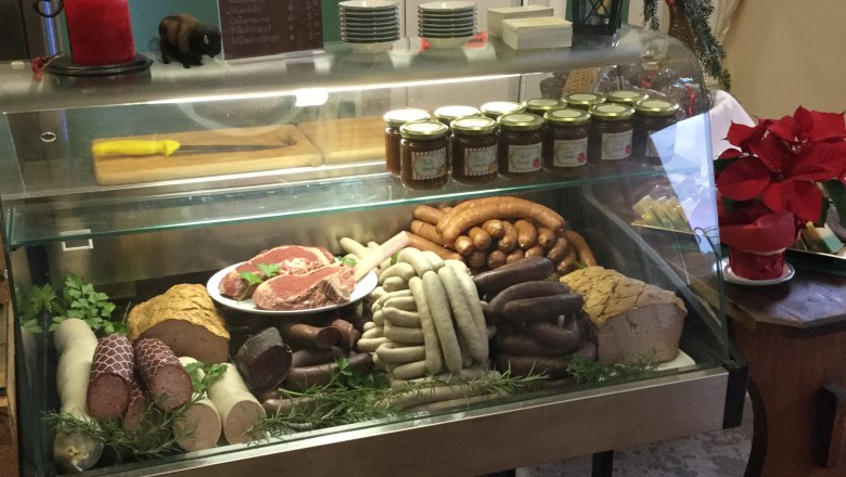 Eine Fleischtheke in einem Hofladen mit verschiedenen Wurstsorten, Fleischst&uuml;cken und Gl&auml;sern mit Aufstrichen.