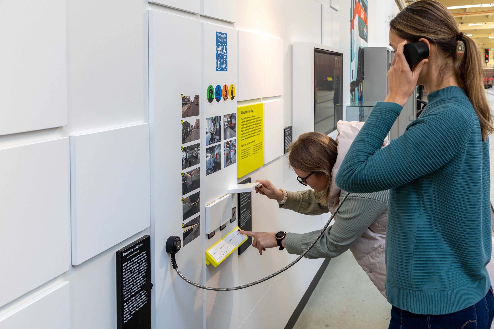 Zwei Frauen interagieren mit einer Ausstellung im Verkehrsmuseum der Wiener Linien.