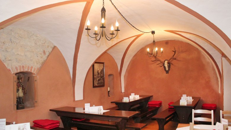 Rustic restaurant with vaulted ceiling, wooden tables and deer antlers on the wall.