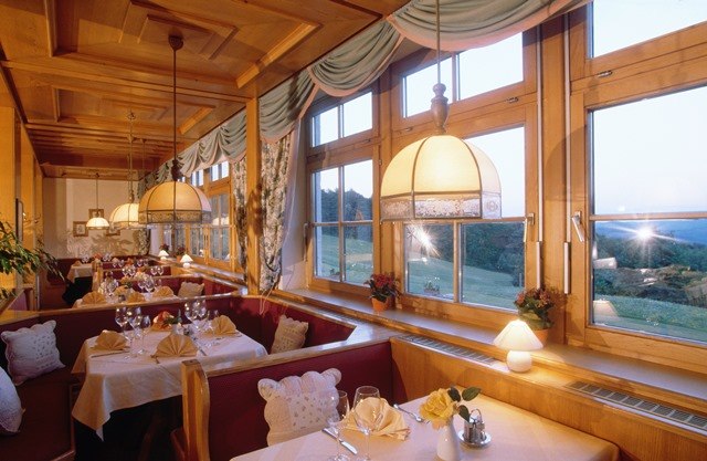 Gemütliches Restaurant mit Holzeinrichtung und großen Fenstern mit Blick auf die Landschaft.