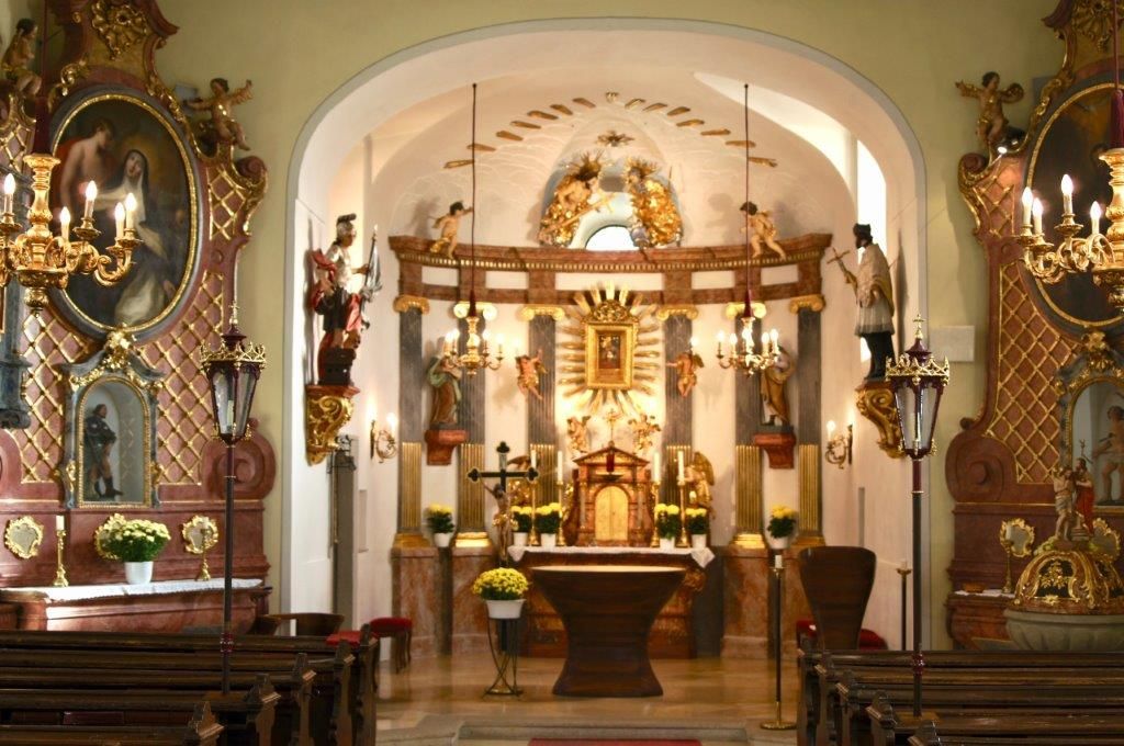 Innenraum einer reich verzierten Kirche mit Altar und Statuen.