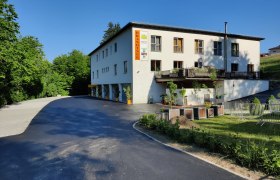 Geb&auml;ude mit der Aufschrift 'Brandtner', umgeben von B&auml;umen und einem Parkplatz.