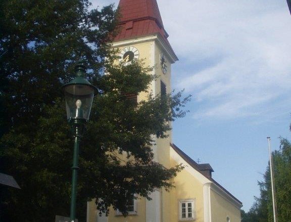 Außenansicht der Pfarrkirche Sulz mit Turm und Uhr.
