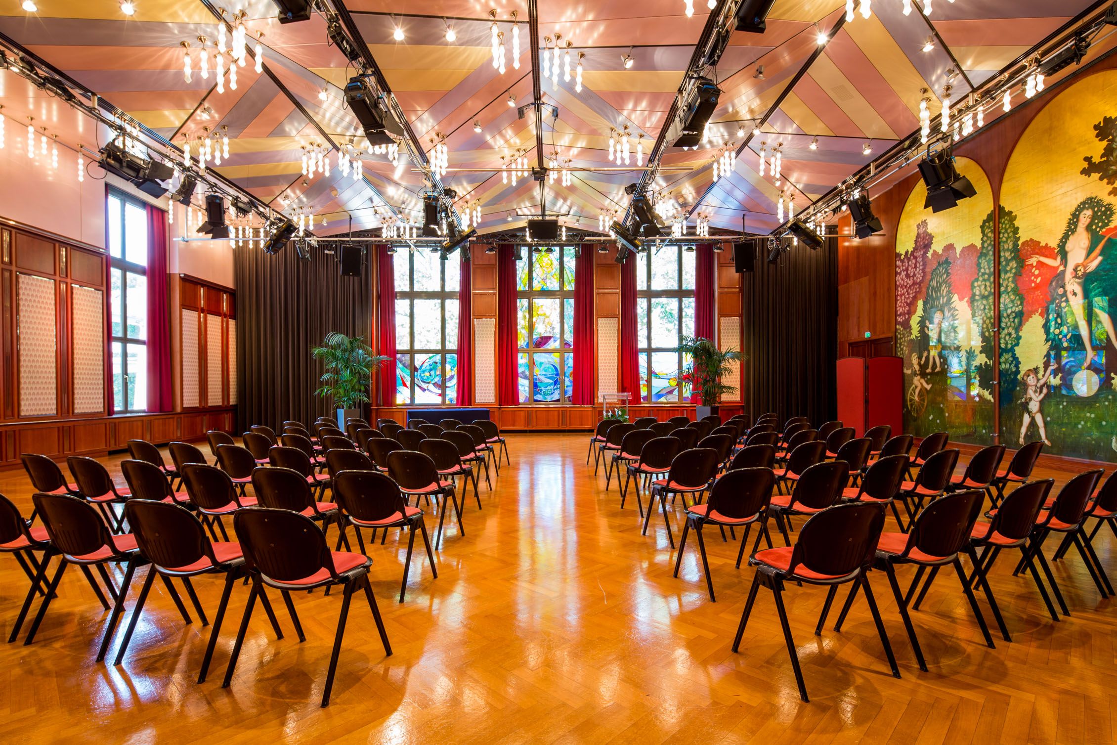 Innenansicht des Casineums im Congress Center Baden mit Stuhlreihen und bunter Wanddekoration.