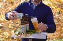 Arrangiert auf einem Tisch im herbstlich verfärbten Wienerwald wird das Wienerwaldbier in ein Glas gefüllt.
