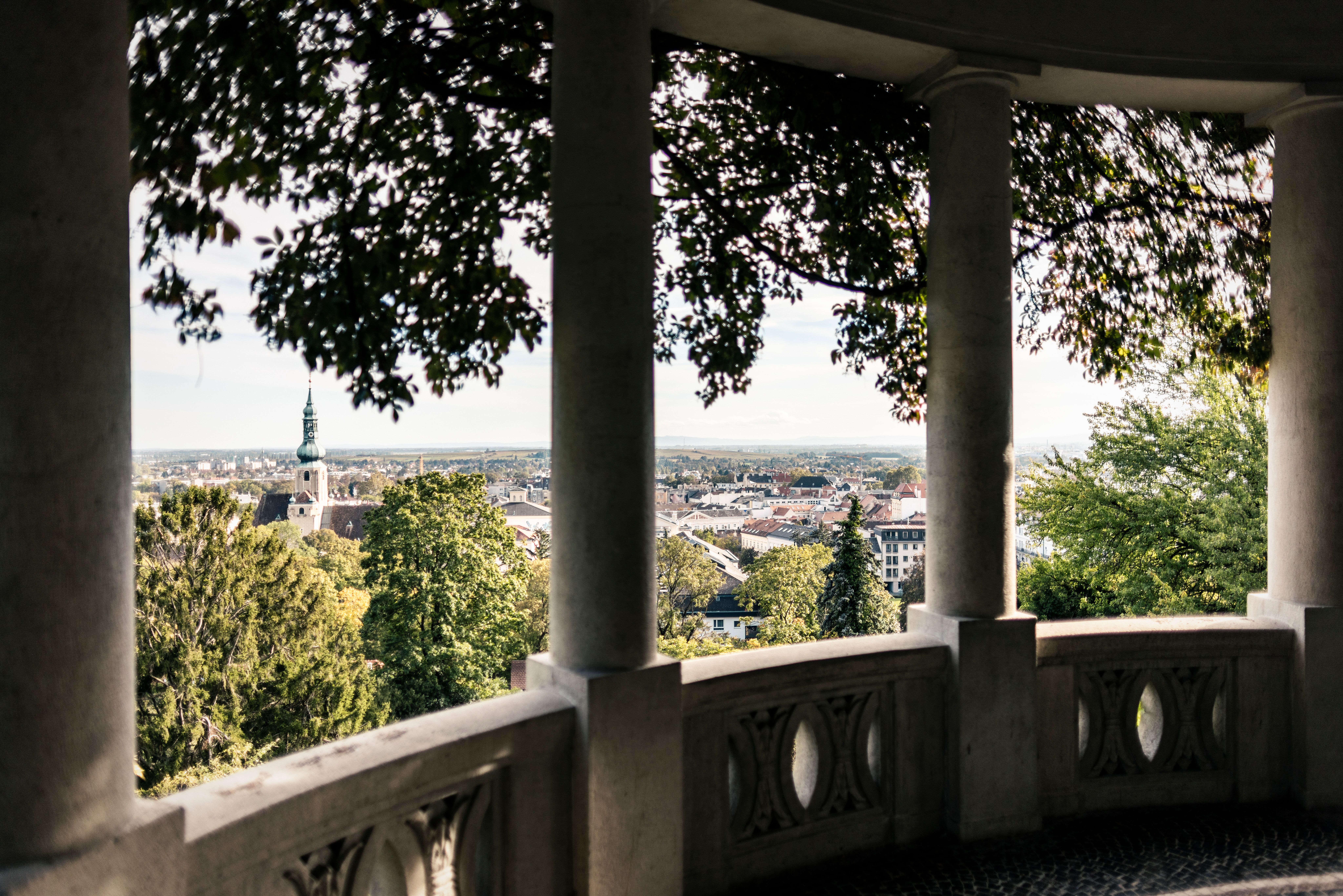 Von dieser malerischen Aussichtsplattform aus eröffnet sich ein atemberaubender Blick über die sanften Hügel und die charmante Stadt. Die üppigen Bäume spenden Schatten und laden dazu ein, die Ruhe der Natur zu genießen. Ein perfekter Ort, um die Seele baumeln zu lassen und die Schönheit der Umgebung zu erleben.
