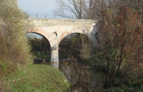 Old stone bridge over a small river, surrounded by trees in the fall.