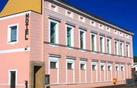 Ein rosa Gebäude mit der Aufschrift 'Hotel' an der Fassade.