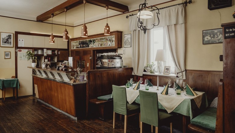 Gemütliches Café mit Holzmöbeln, gedecktem Tisch und Barbereich.