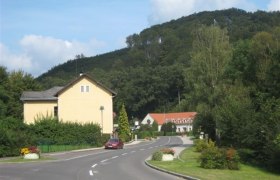 Rural road with houses and wooded hill in the background.
