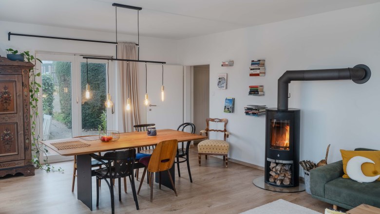 Modernes Wohnzimmer mit Esstisch, Stühlen, Kamin und Bücherregalen.