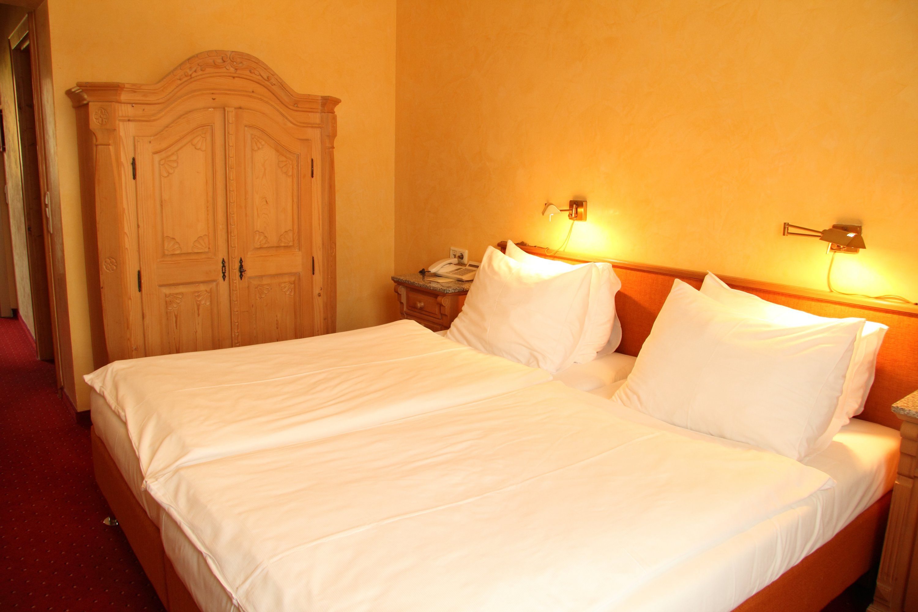 Hotelzimmer mit Doppelbett, Holzmöbeln und warmem Licht.