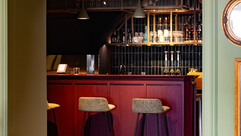 Elegante Bar mit roten Holzmöbeln und hohen Stühlen.