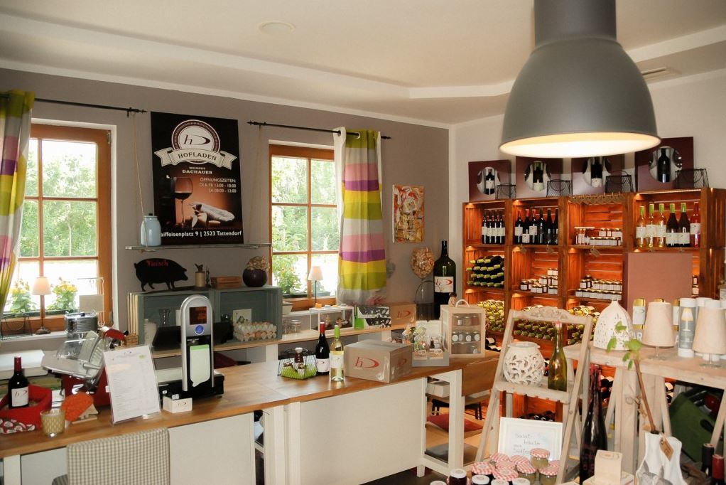 Innenansicht eines Hofladens mit Regalen voller Weinflaschen und Produkten.