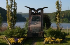 Denkmal von Wilhelm Kress in Tullnerbach vor einem See.