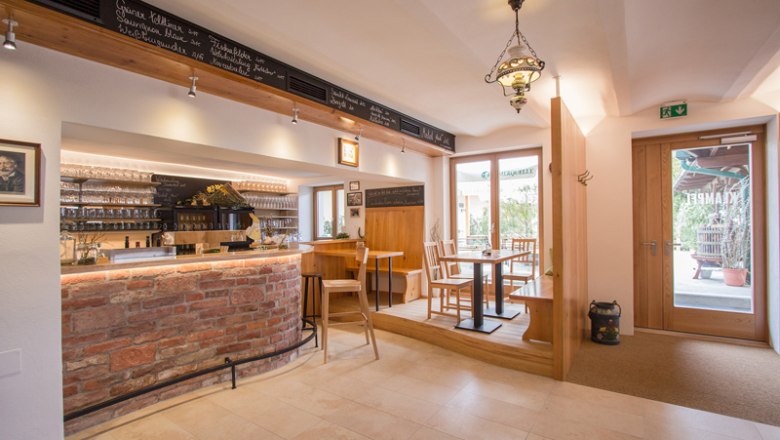 Innenansicht einer gem&uuml;tlichen Weinbar mit Holzm&ouml;beln und Ziegeltheke.