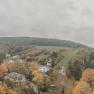 View of an autumnal landscape with hills, houses and trees.