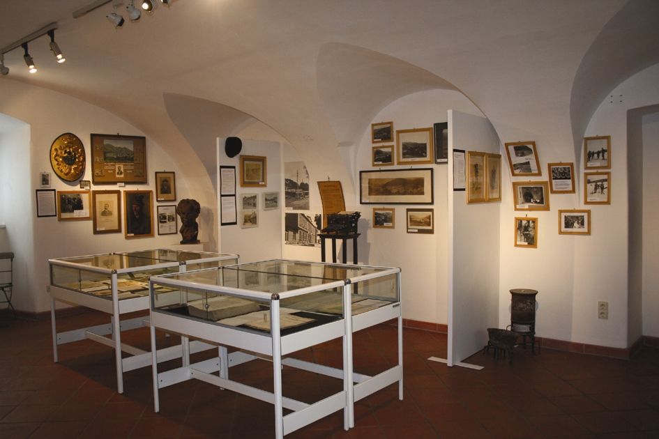 Innenansicht eines Museumsraums mit Vitrinen und historischen Fotos an den Wänden.