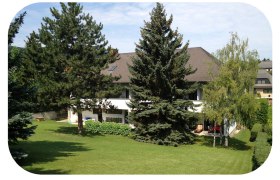 Rückansicht eines Gasthofs mit Garten und Bäumen.