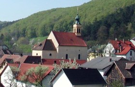 Wallfahrtskirche Maria Raisenmarkt in einer ländlichen Umgebung mit Hügeln im Hintergrund.